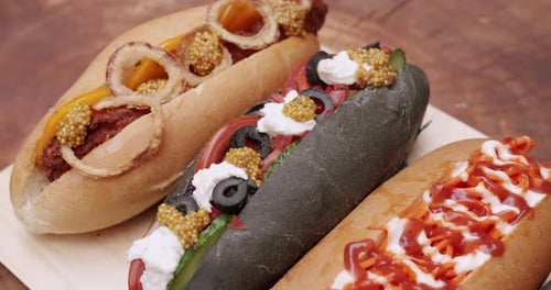 Gourmet Hot Dogs With Toppings On Wooden Board
