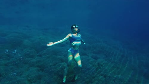 Woman Swims Underwater in the Tropical Sea and Slowly Moves Near the Sea Bottom