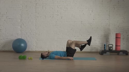 Man Fitness Trainer in Sportswear Doing Legs Cycle Abs Exercise for Online Class at the Home Studio