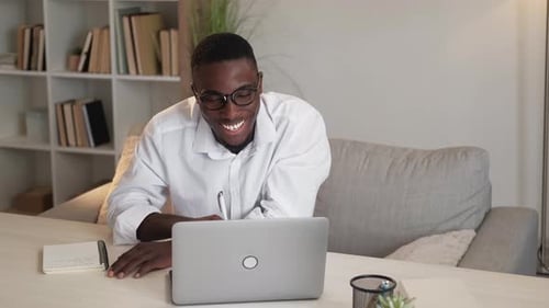 Young Adult Working Remotely with Laptop and Notebook