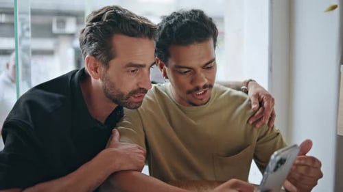 Homosexual Partners Watching Cellphone Screen Sitting Modern Cafe Close Up