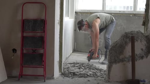 A man works with a jackhammer in an apartment. Work with a perforator