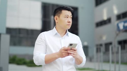 Successful asian business man standing the city street background of urban office building using