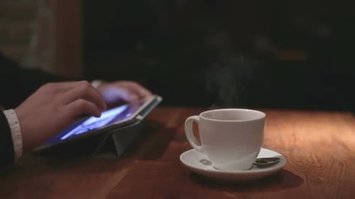 Man with Tablet Computer Reading Information the Evening in Cafe Shop