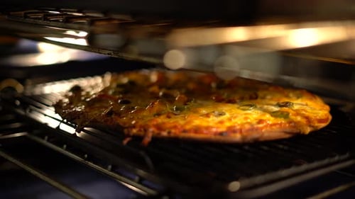 Pulling out pizza from oven at home. Taking out pizza from hot oven with oven mitts gloves. Homemade