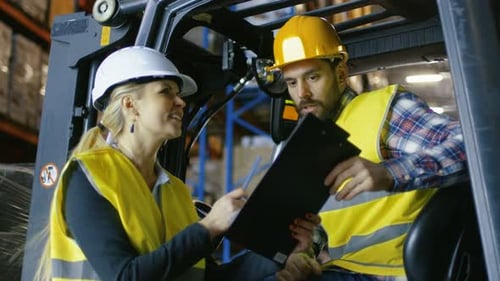 Female Manager Gives Work Assignment to Forklift Driver. They're in a Big Warehouse Full of Pallet