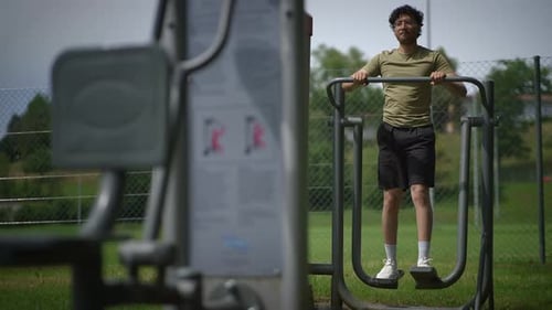 Outdoor Fitness A Young Man Actively Engaging in a Workout at Community Gym Equipment