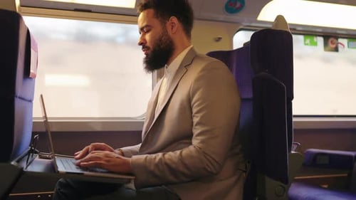 Ein Geschäftsmann, der während seiner Reise im Zug fleißig an seinem Laptop arbeitet