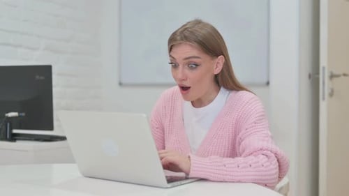 Excited Woman Celebrating Achievement Using Laptop Indoors