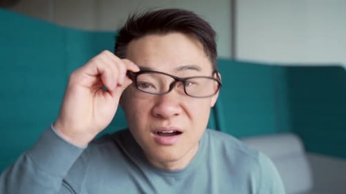 Man Takes off Glasses, Expresses Shock and Smiles