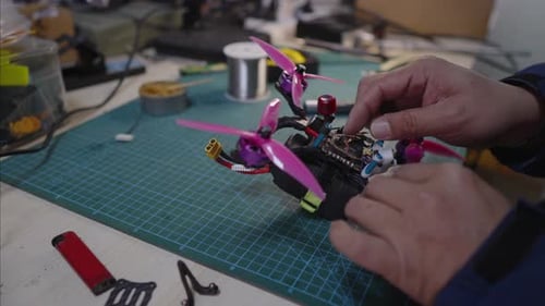 Echnician Assembling FPV Drone Components on Factory Workbench Installing Propellers and Electronic