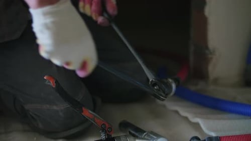 Tradesman Tightening Pipes with Wrench Indoors
