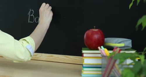 Woman writing phrase Back To School on blackboard indoors, closeup