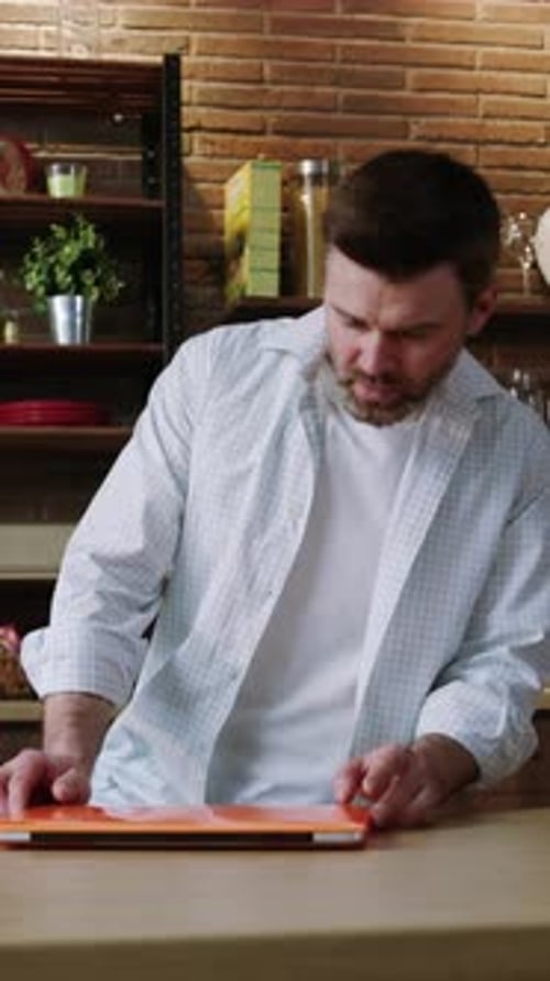 Adult Man Typing on Laptop in Modern Kitchen