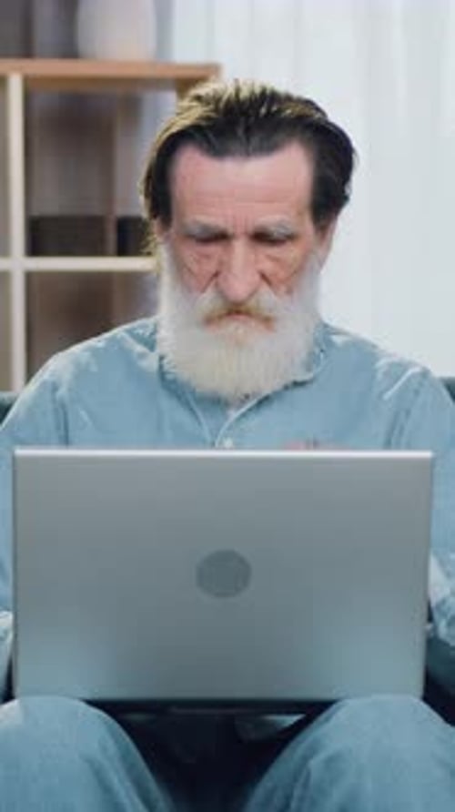 Senior Man Uses Laptop in Bright Home Interior