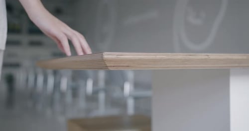 Mano estirando la mano para tocar un estante de madera en una habitación moderna