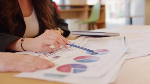 Woman Reviewing Charts at a Table Indoors