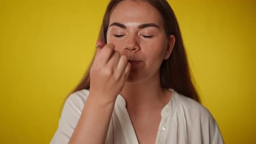 Woman Eating with Spoon on Yellow Background