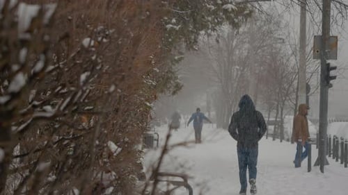 Snow covers the city streets as people navigate through winter conditions