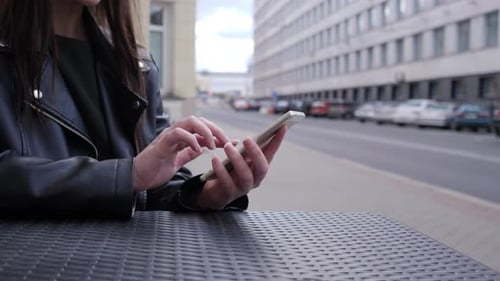 Woman Uses Mobile Phone at Outdoor Table