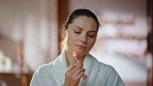 Woman Using Pink Facial Roller on Face