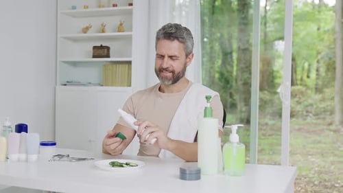 Man Examines Skincare Products at Table Indoors Daytime