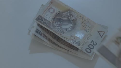 Man's hand stacking different zloty banknotes on a desk at night moonlight
