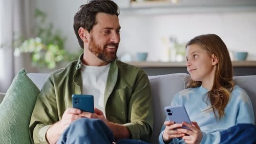 Father and Daughter Relaxing at Home with Smartphones