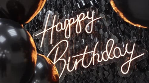 Neon inscription "Happy birthday" on a background of shiny black sequins and helium balloons.