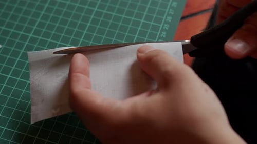 Hands Cutting Gray Fabric with Scissors, Closeup