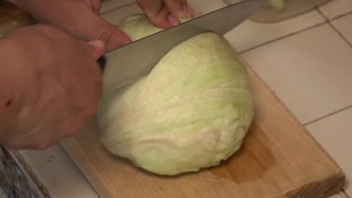 Cutting Iceberg Lettuce with Knife on Cutting Board
