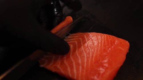 Gloved Hand Slicing Fresh Salmon Fillet