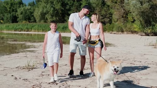 Maman, papa et enfant heureux profitent des vacances d'été avec le chien Akita Inu sur la plage