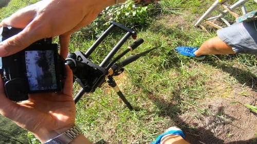 Videographer setting up his DSLR on curved slider for shooting outdoors. View from above.