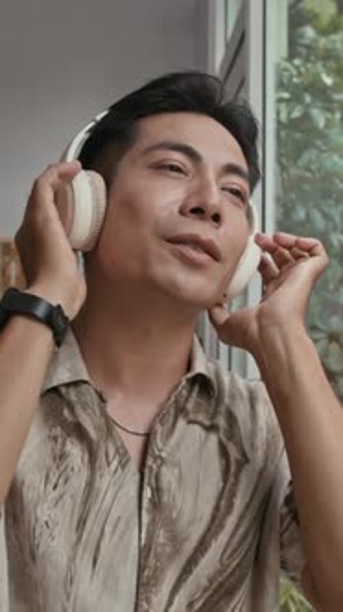 Young Adult Listens to Music with Headphones Indoors