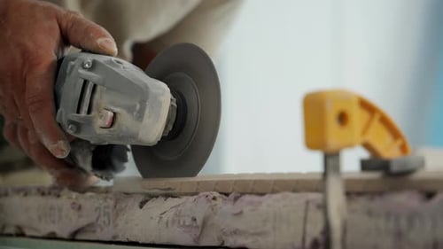 Worker is Cutting a Ceramic Tile with an Electric Angle Grinder Workshop or Renovation Site Focusing