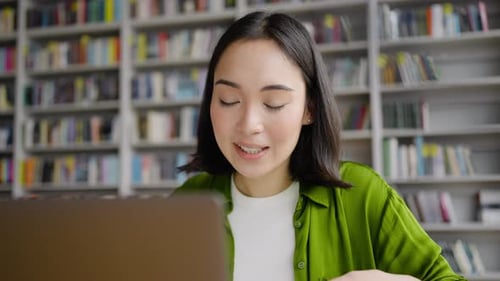 Young Female Teacher Conducts Online Lesson From Library