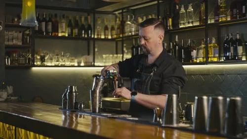 A Bartender Mixes Alcohol at the Bar to Prepare Delicious Cocktails
