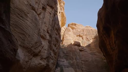 Sunlit Narrow Canyon Path Surrounded By Massive Sandstone Rock Walls