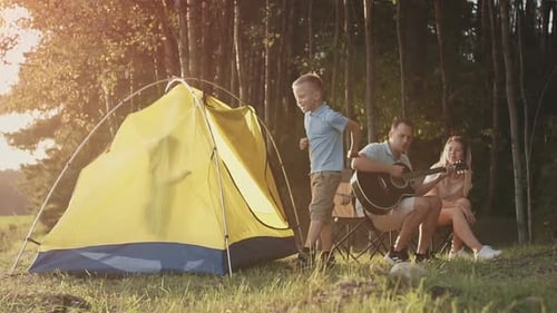Family Camping in Forest with Guitar at Sunset