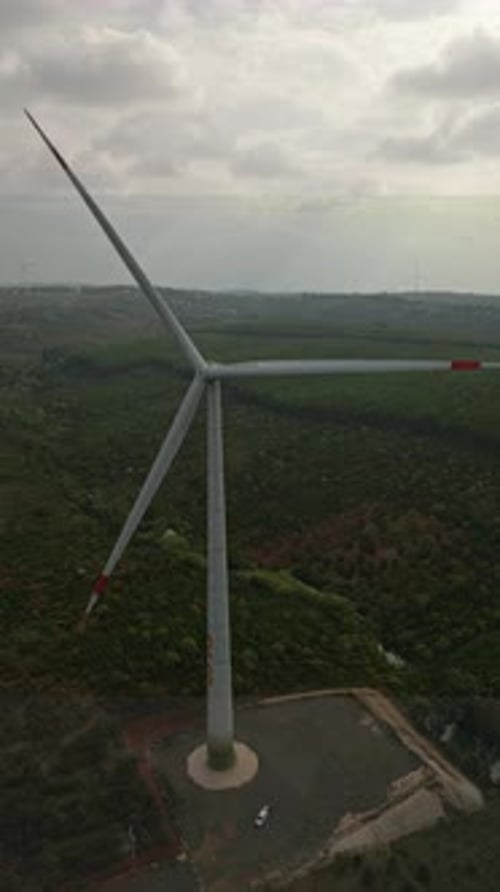 Wind turbine rotating at wind farm, vertical video. Windmill generating clean green energy, drone po