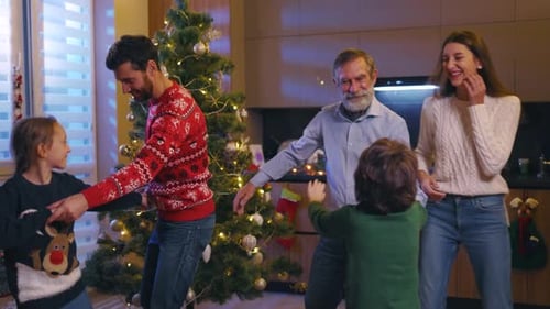 Family dancing in living room near Christmas tree