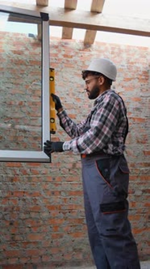 Construction Worker Installing a Window with Spirit Level