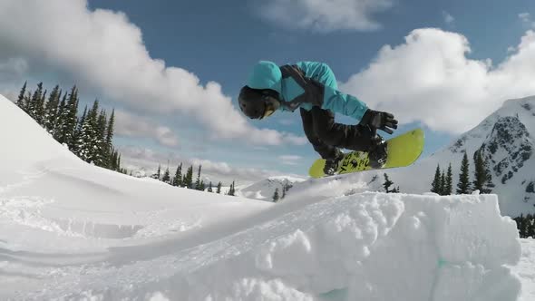 snowboarder spinning a 360 with a grab over a jump in the backcountry ...