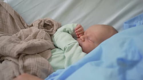 A Cute Newborn Baby Sleeps Peacefully on a Clinic Bed Beside Their Mother A Serene and Heartwarming