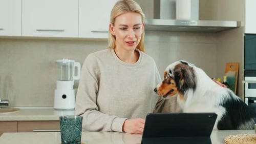 Woman Talking on Tablet with Dog in Kitchen