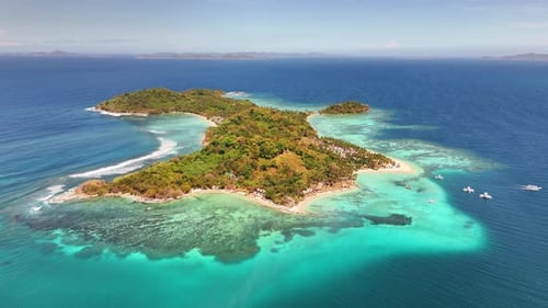 Aerial view of Darocotan Island, Palawan, surrounded by turquoise reef-filled waters in Philippines