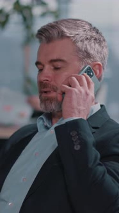Man in Suit Talking on Phone at Desk