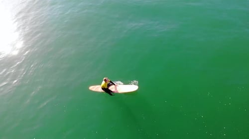 Surfer Zander Adelsohn paddles to catch a wave in Pacific Ocean at Huntington Beach in surfing compe