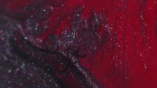 Abstract Glittery Black and Red Paint Slowly Swirling Together